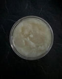 White sparkly sugar scrub in clear jar with black ribbed lid.