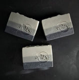 Soap bar that has stripes from gray (top) to black (bottom). 