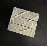 Soap bar that has stripes from gray (top) to black (bottom).  Top down view reveals linear design on top.