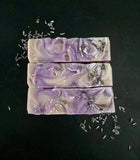 Purple swirled soap scented in lavender and chamomile topped with glitter and dried lavender buds, top view